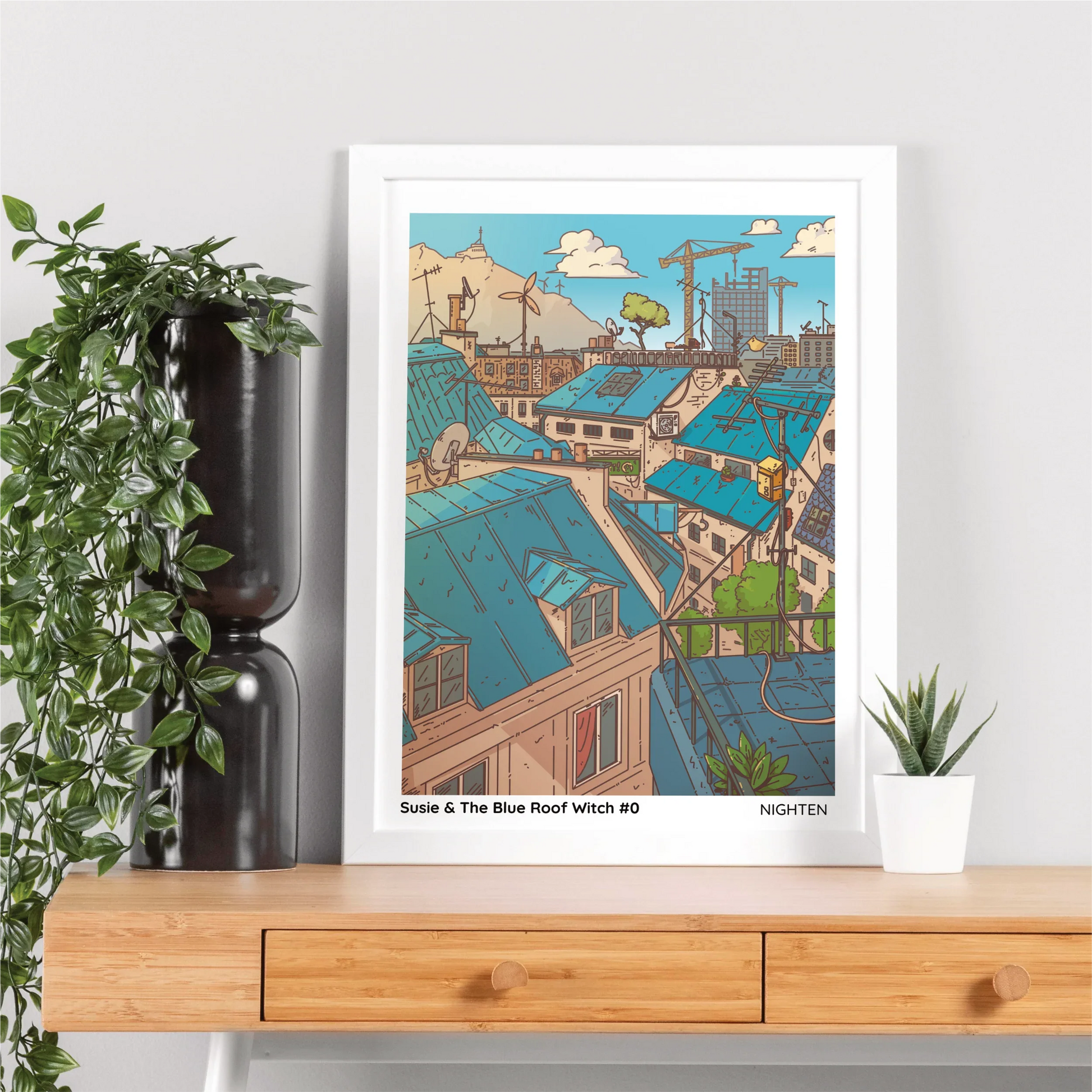 Framed artwork of a cityscape with blue roofs on a wooden shelf.